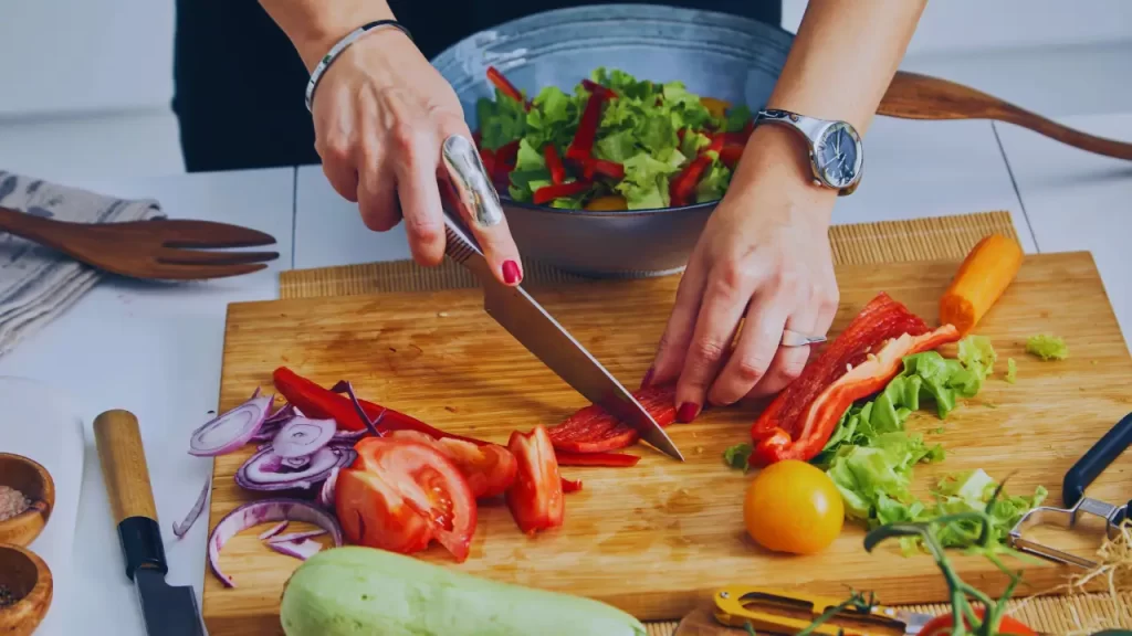 Pessoa organizando marmitas saudáveis, com legumes.