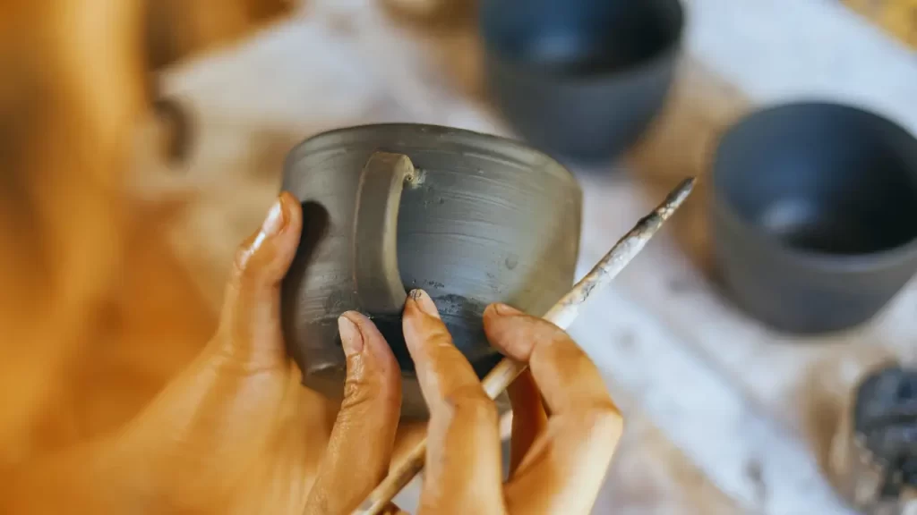 Mãos pintando caneca feita de cerâmica fria para iniciantes