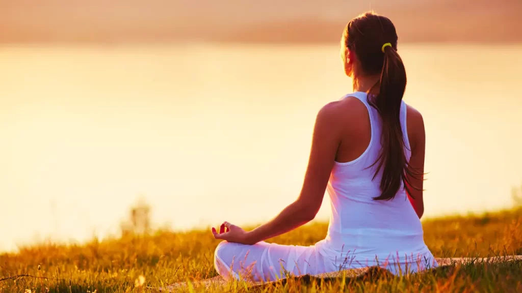 Pessoa meditando ou sentada em um espaço natural, sem celular à vista.