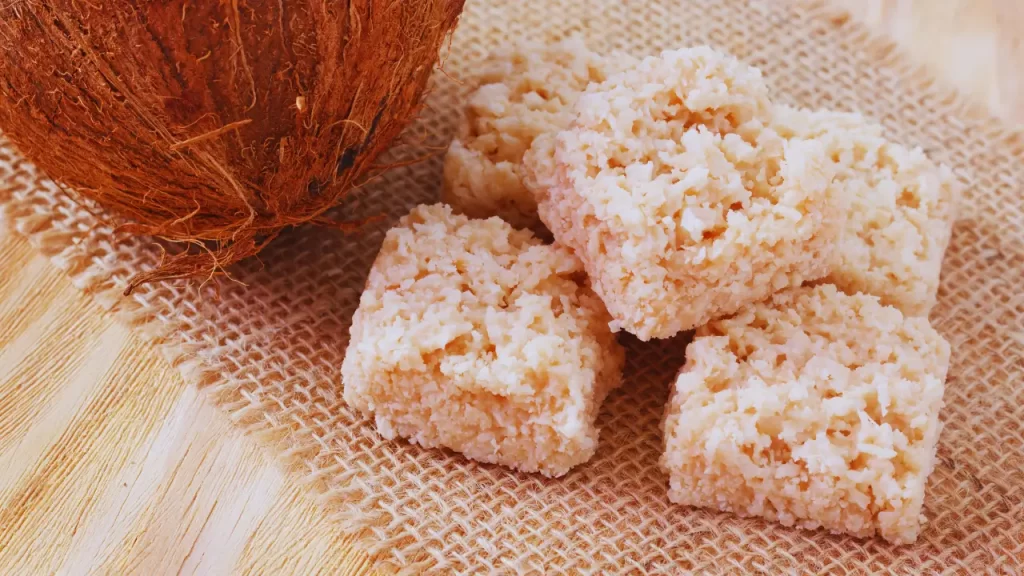 Cocada branca cremosa cortada em quadrados sobre papel manteiga
