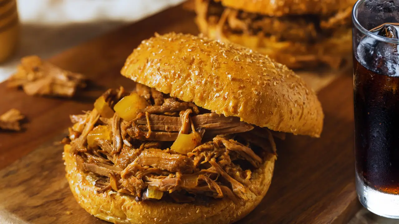 Carne louca de panela dourada servida em prato branco com pão