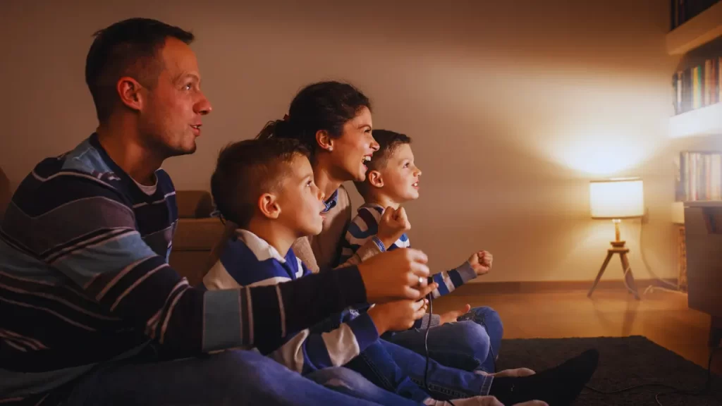 Família jogando videogame cooperativo juntos no sofá